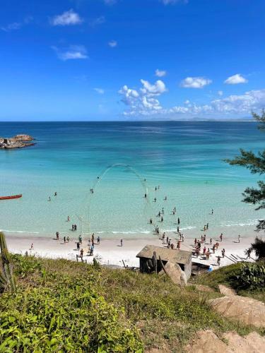 a group of people on a beach with the ocean at Casa e Kitnet - Praia Grande Centro in Arraial do Cabo