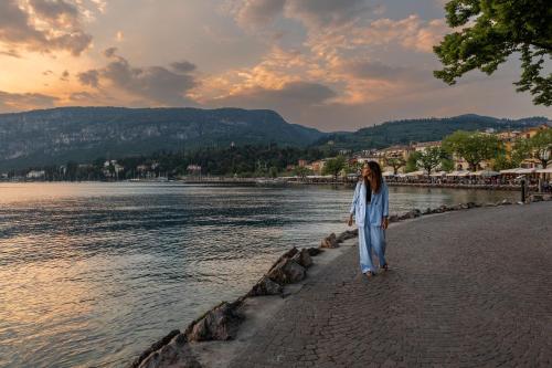 a woman walking on the shore of a body of water at Hotel Italia in Garda