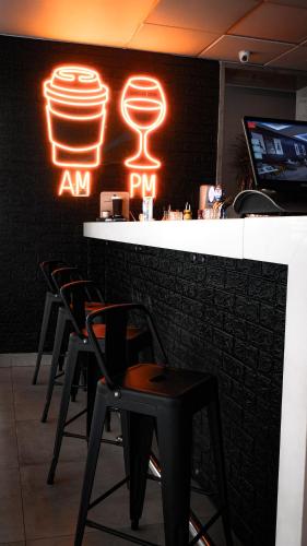 a bar with four black chairs and a neon sign at ibis Santiago Providencia in Santiago