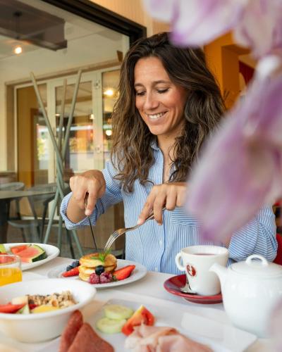 a woman sitting at a table eating food at Hotel Italia in Garda