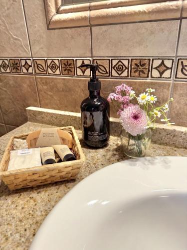 a bathroom sink with a bottle of soap and flowers at Agroturismo Sa Marina - Adults Only in Cala Boix