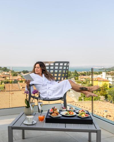 a woman is sitting in a chair reading a paper at Hotel Italia in Garda