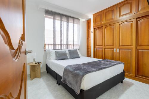 a bedroom with a bed with wooden cabinets and a window at Parque de Envigado a 350 mts, 2bd, 500mb internet in Envigado