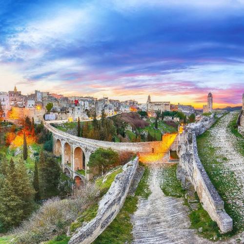 an old stone bridge over a river in a city at Le Segrete in Gravina in Puglia