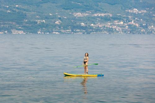 a woman standing on a paddle board in the water at Hotel Italia in Garda