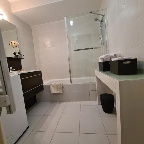 La salle de bains blanche est pourvue d'une douche et d'une baignoire. dans l'établissement Magnifique T3 Port Fréjus 2, à Fréjus