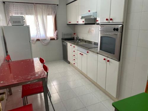 Una pequeña cocina con gabinetes blancos y un refrigerador. en Playa Panxón Mar, en Nigrán