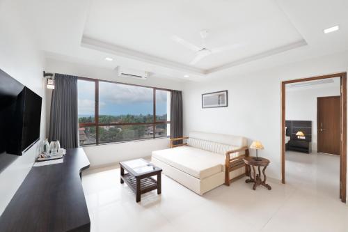 a living room with a couch and a large window at BSG Porvorim Regency Hotel Goa in Porvorim