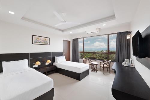 a hotel room with two beds and a balcony at BSG Porvorim Regency Hotel Goa in Porvorim
