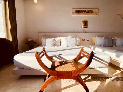 a bedroom with two beds and a wooden chair at Hotel Para Ti - Adults Only in Holbox Island
