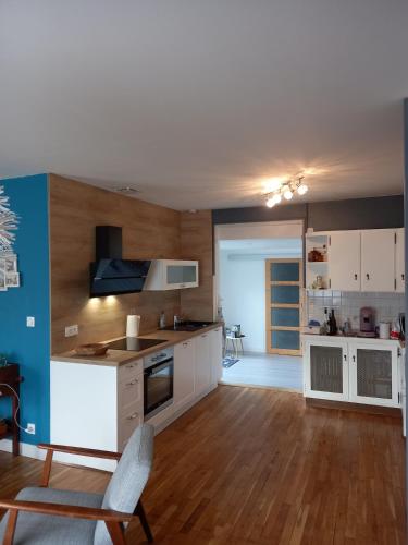 une cuisine avec des armoires blanches et un mur bleu dans l'établissement La Maison de Valérie, à La Flèche