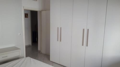 a white bedroom with white cabinets and a bed at Appartamento Morelli Beach - Via Trento 7 in Follonica