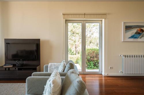 a living room with a couch and a tv at Casa dos Ciprestes in Ericeira