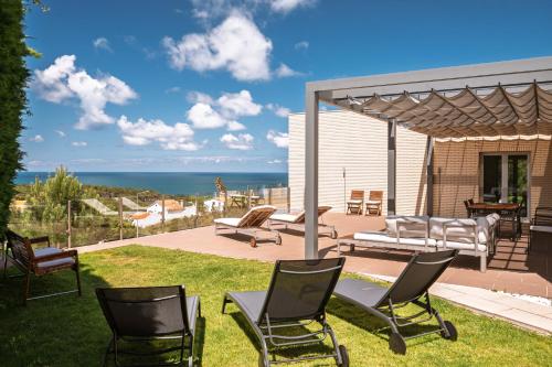 a yard with chairs and a patio with a view of the ocean at Casa dos Ciprestes in Ericeira