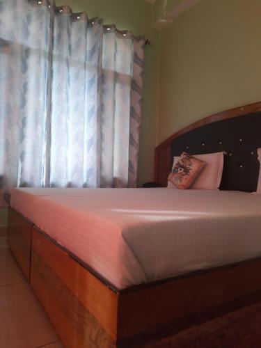 a bedroom with a wooden bed with a window at The Wangdu in Rewalsar