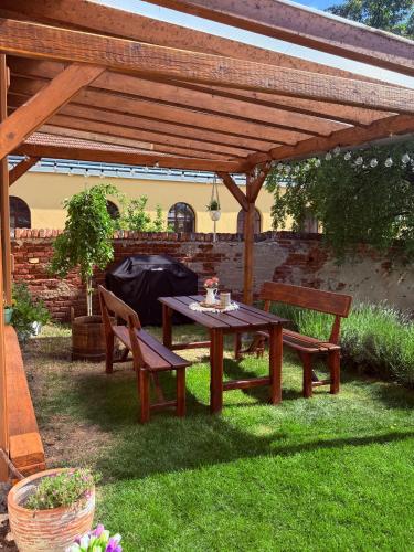 a picnic table and two benches under a wooden pergola at Ubytování TradiceJinak in Dolní Dunajovice