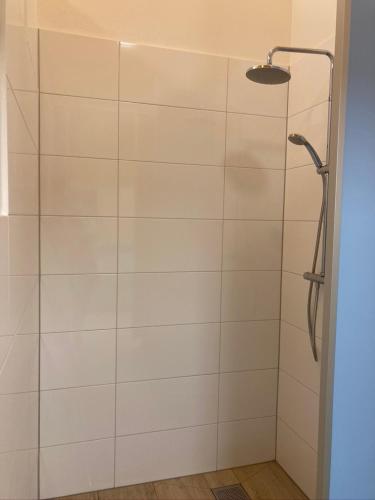 a bathroom with a shower with white tiles at Trekkershut in Jubbega-Schurega