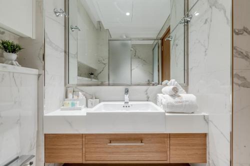 a white bathroom with a sink and a mirror at GLOBALSTAY Azizi Riviera 59 in Dubai