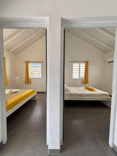 a mirror in a room with two beds at Gîte Tournesol - À 2 min de la plage et du bourg in Anse-Bertrand