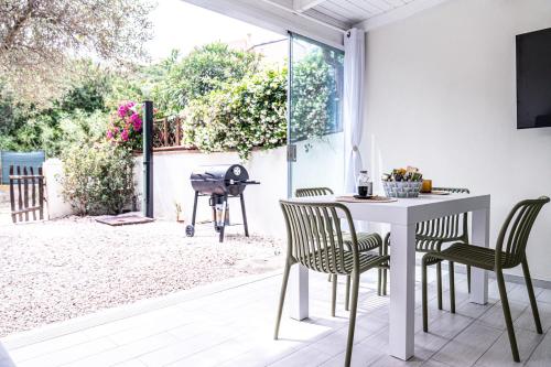 a patio with a table and chairs and a grill at Casa Gemelli a pochi passi da spiaggia Su Giudeu Chia in Chia