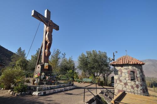a cross in front of a church with a bench at Inca Hoteles in Los Andes