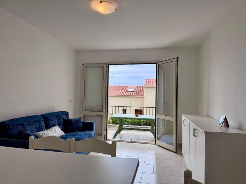 - un salon avec un canapé bleu et une porte coulissante en verre dans l'établissement I Certali apt 5 apt 6, à LʼÎle-Rousse