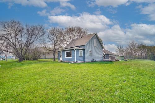 a blue house in a field of green grass at Serene Devils Lake House with Deck and Fire Pit! in Devils Lake