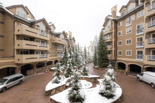 a parking lot with snow covered trees in a courtyard at St. James Place in Beaver Creek