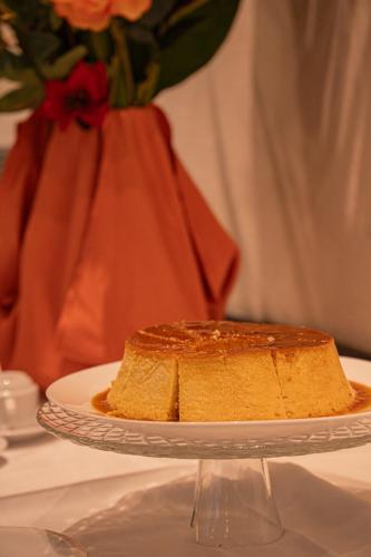 a cake on a plate on a table with a vase at Hotel Porto Napolis in Eunápolis