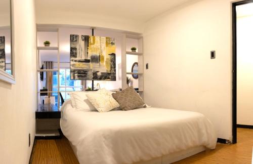 a bedroom with a bed with white sheets and pillows at Best location in Mexico City Cozy Master Suite in Mexico City