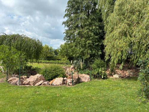 a garden with rocks in the grass and trees at Gîte au Bon Accueil Therence in Sainte-Thérence