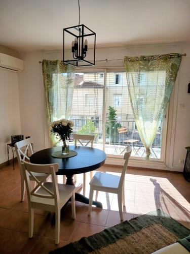 une salle à manger avec une table et des chaises et une fenêtre dans l'établissement ARLES a 2 pas des rencontres de la PHOTOGRAPHIE ,Appartement refait completement a neuf , pour 4 personnes, à Arles