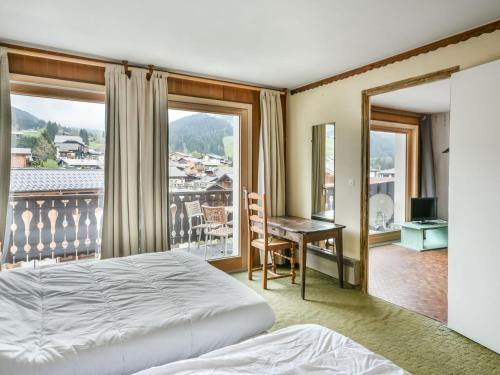 une chambre avec un lit et un bureau et un balcon dans l'établissement Appartement 1 chambre, proche centre, parking et équipements modernes - FR-1-685-82, aux Gets