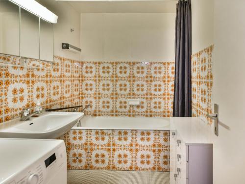 La salle de bains orange et blanche est pourvue d'un lavabo et d'une baignoire. dans l'établissement Appartement 1 chambre, proche centre, parking et équipements modernes - FR-1-685-82, aux Gets