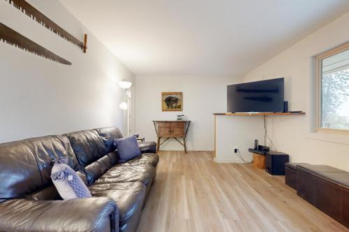 a living room with a leather couch and a flat screen tv at Gold Rush Deck in Coeur d'Alene