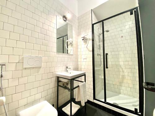 a white tiled bathroom with a sink and a shower at YellowSquare Milan in Milan