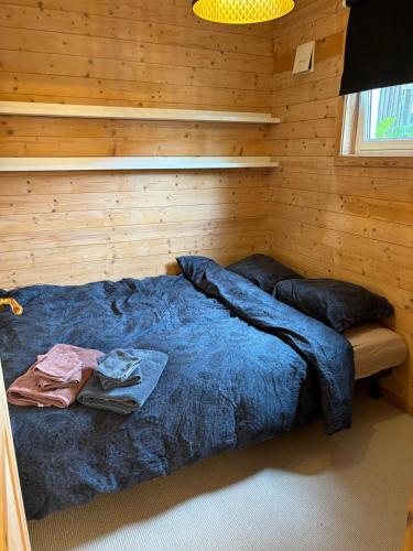 a bedroom with a blue bed in a wooden wall at Child friendly basement apartment in Stavanger
