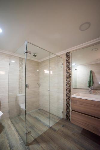 een badkamer met een glazen douche en een wastafel bij Belén Vibe in Medellín