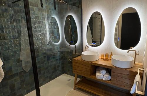 La salle de bains est pourvue de 2 lavabos et d'une douche avec miroirs. dans l'établissement Le Clos des Pins, à Andernos-les-Bains
