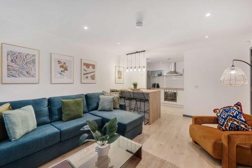 a living room with a blue couch and a kitchen at Baltic Apt II - City Centre with Parking, Sleeps 6 in Liverpool