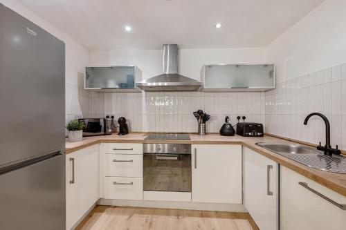 a kitchen with white cabinets and a sink at Baltic Apt II - City Centre with Parking, Sleeps 6 in Liverpool