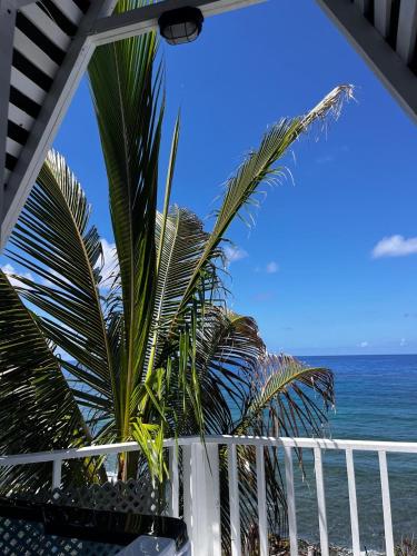 a balcony with a view of the ocean and palm trees at The Sea Cliff Hotel Resort & Spa in Port Antonio