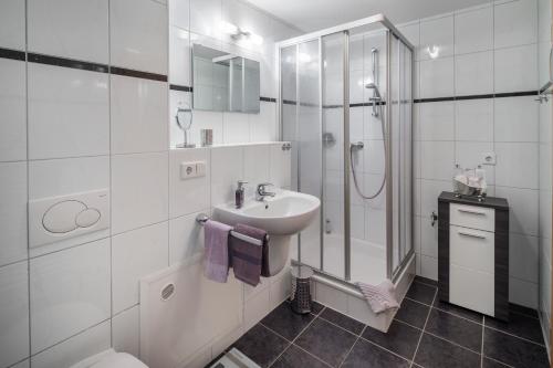 La salle de bains blanche est pourvue d'un lavabo et d'une douche. dans l'établissement Apartment Emsköpken, à Norderney