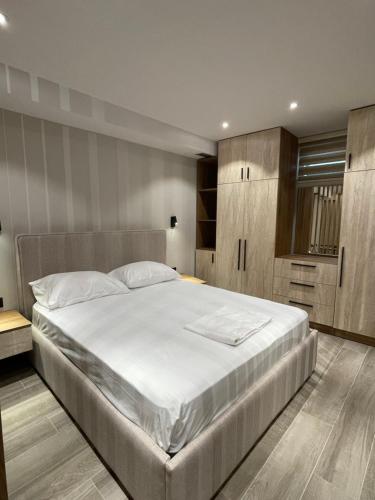a bedroom with a large white bed and wooden cabinets at Tirana Elite Apartments in Tirana