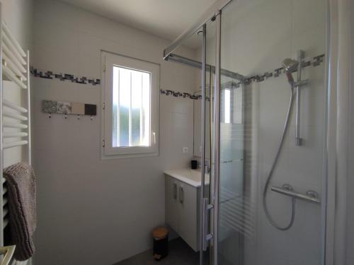 une salle de bain blanche avec une douche et un lavabo dans l'établissement Maison La Rose des Vents, avec WIFI, proche plage et commerces, à Brem-sur-Mer