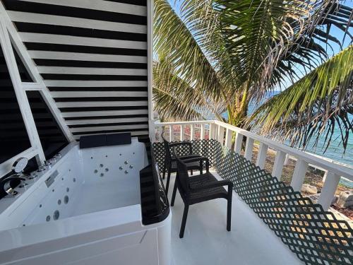 a balcony with two chairs and a palm tree at The Sea Cliff Hotel Resort & Spa in Port Antonio