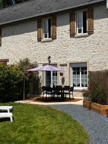 une table avec un parasol devant un bâtiment dans l'établissement Le Moulin de la Fosse Soucy 