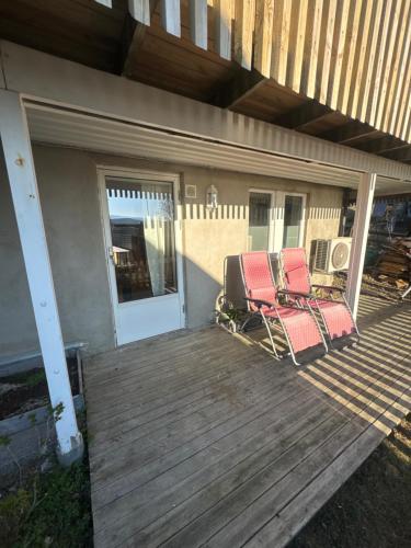 two chairs sitting on a deck next to a house at 3 roms 10 km fra Tromsø sentrum in Tromsø