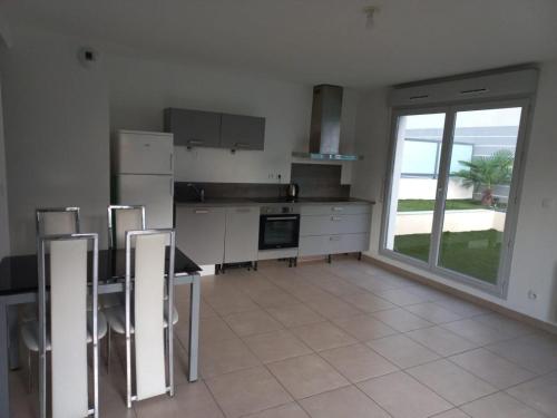 une cuisine avec une table et des chaises ainsi qu'une grande fenêtre dans l'établissement T2 Villefranche, à Villefranche-sur-Saône