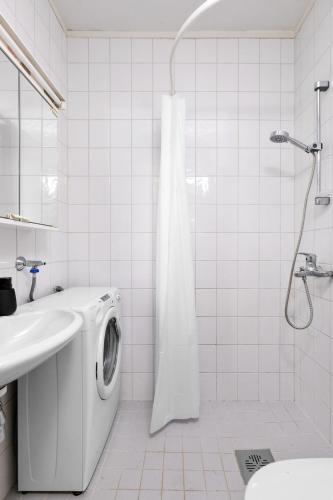 a white bathroom with a washing machine and a sink at Apartment in central Helsinki in Helsinki